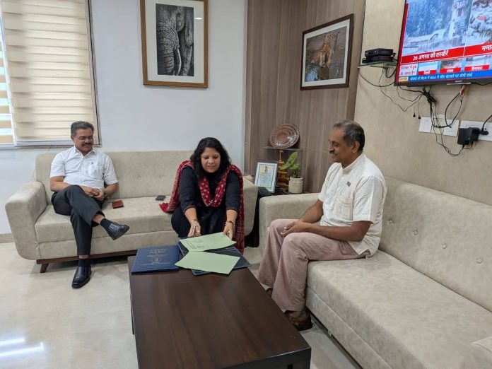 Three officials seated in an office discussing and reviewing documents related to adventure and ecotourism partnership in Madhya Pradesh.”